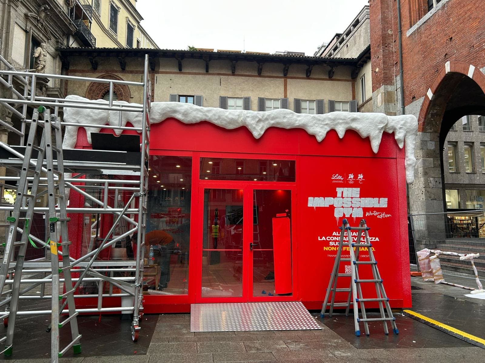 Temporary store rosso con decoro effetto neve, montaggio in piazza con ponteggio